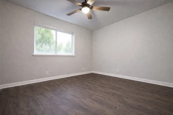 a view of an empty room with wooden floor and a window