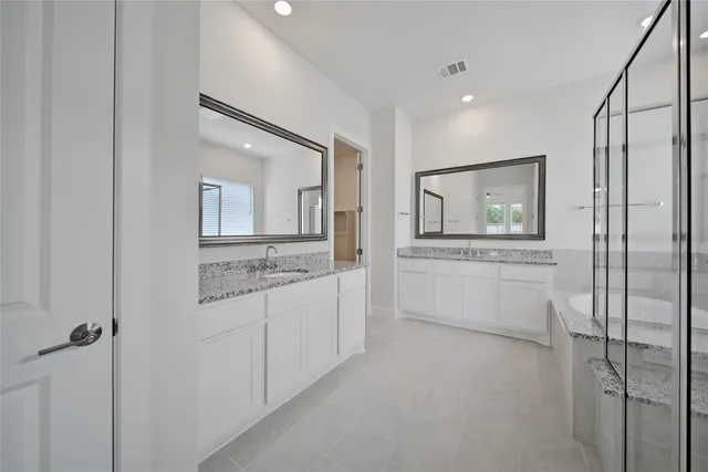 a spacious bathroom with a granite countertop tub sink shower and mirror