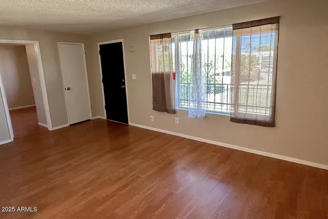 an empty room with wooden floor and windows
