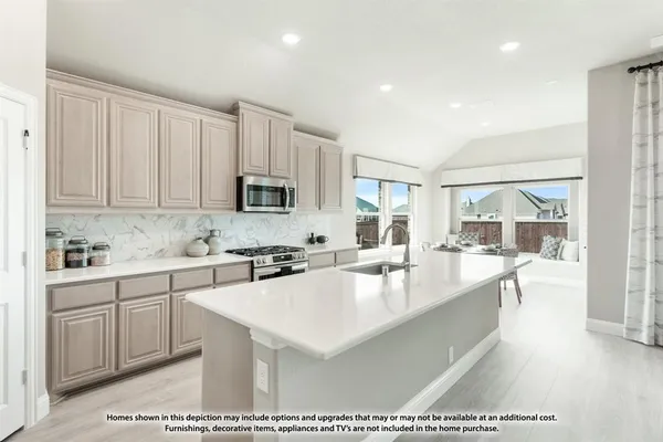 a large white kitchen with granite countertop a stove a sink a refrigerator and white cabinets with wooden floor