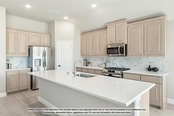 a kitchen with stainless steel appliances a sink a stove a microwave a center island and cabinets