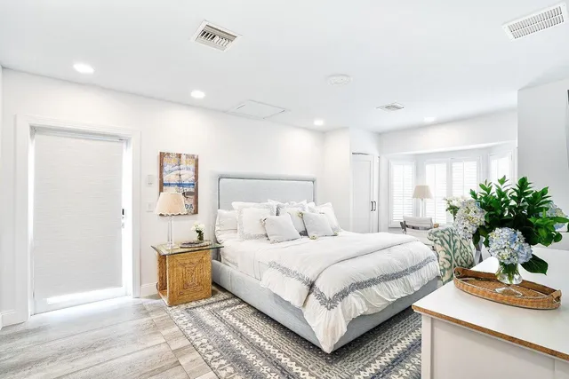 a bedroom with a bed and a potted plant on the dresser