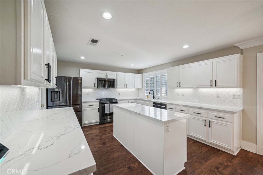 2575 Gilbert Avenue Corona, CA 92881 - Photo 14 of 58 a large kitchen with stainless steel appliances kitchen island a stove a refrigerator a sink dishwasher and a dining table with wooden floor