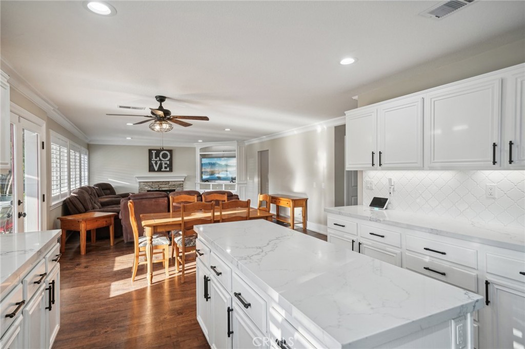 2575 Gilbert Avenue Corona, CA 92881 - Photo 17 of 58 a large white kitchen with a stove a sink a dining table and chairs with wooden floor