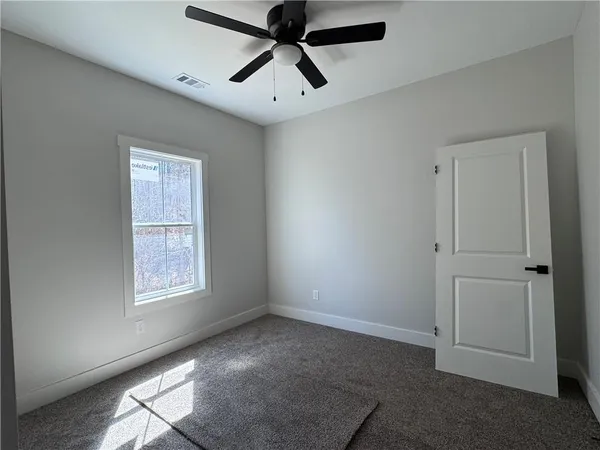 an empty room with windows and fan