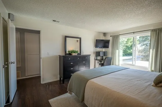a bedroom with a bed and a flat tv screen on dresser