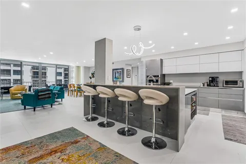 a large white kitchen with stainless steel appliances kitchen island a large counter top and a stove