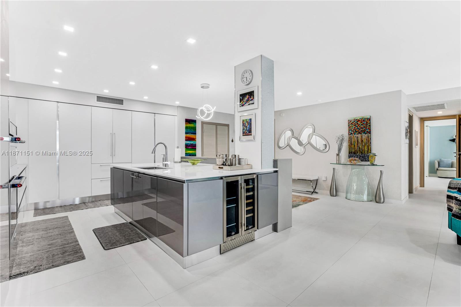 10155 Collins Avenue, Unit 606 Bal Harbour, FL 33154 - Photo 13 of 48 a large white kitchen with stainless steel appliances kitchen island a large counter top and a stove