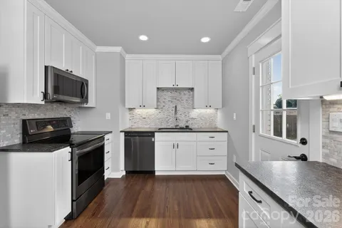 a kitchen with granite countertop a sink dishwasher stove and microwave with wooden floor