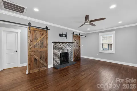 a view of an empty room with wooden floor fireplace and a window