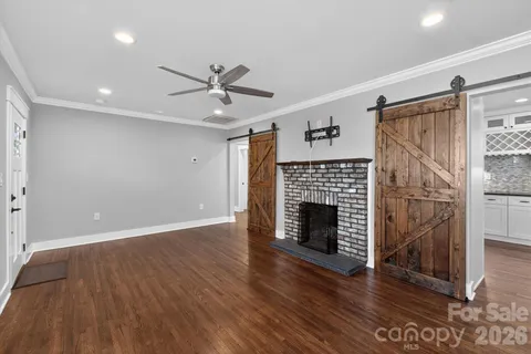 an empty room with wooden floor fireplace and windows