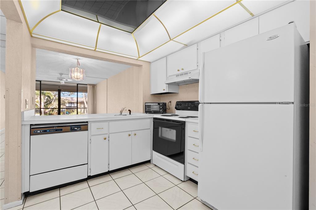 12300 Vonn Road, Unit 1205 Largo, FL 33774 - Photo 5 of 32 a kitchen with white cabinets and white appliances