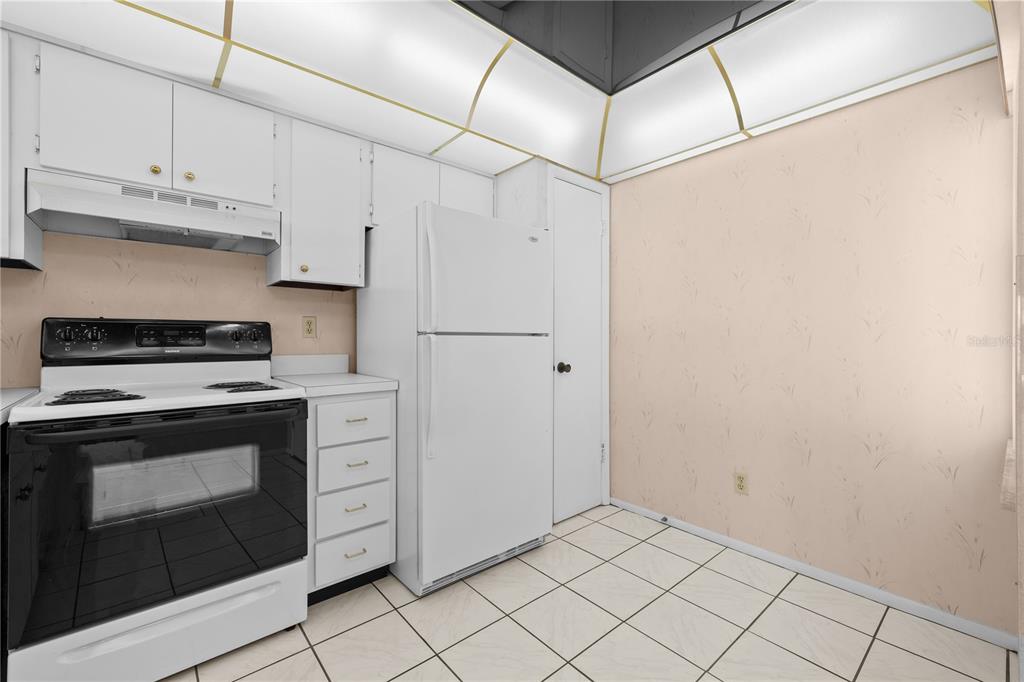 12300 Vonn Road, Unit 1205 Largo, FL 33774 - Photo 6 of 32 a kitchen with white cabinets and white appliances