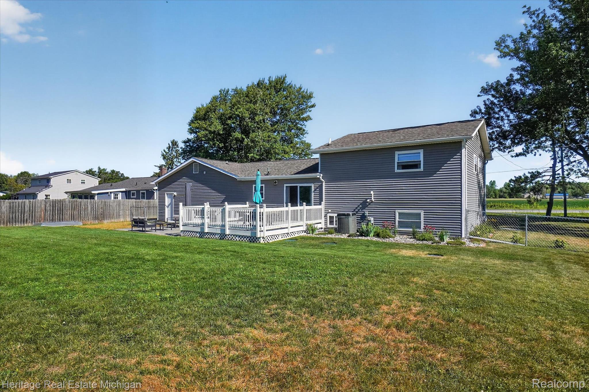 7225 Baldwin Road Swartz Creek, MI 48473 - Photo 34 of 44 Spacious backyard featuring a large wooden deck, sliding glass doors, and a partial chain-link fence