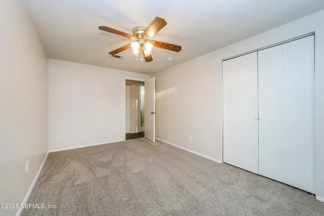 a view of an empty room and chandelier fan