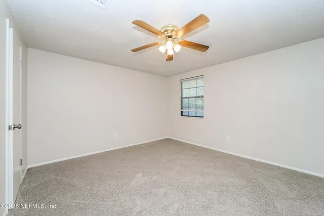 an empty room with window and ceiling fan