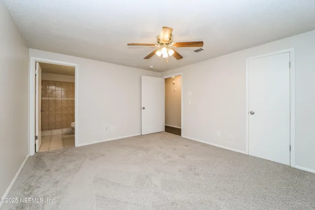 an empty room with closet and a chandelier fan
