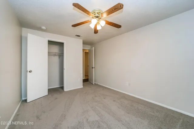 an empty room with fan and a chandelier fan