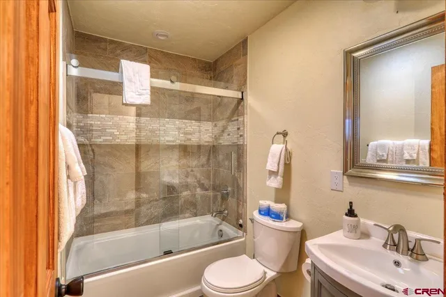a bathroom with a bathtub shower sink mirror and toilet