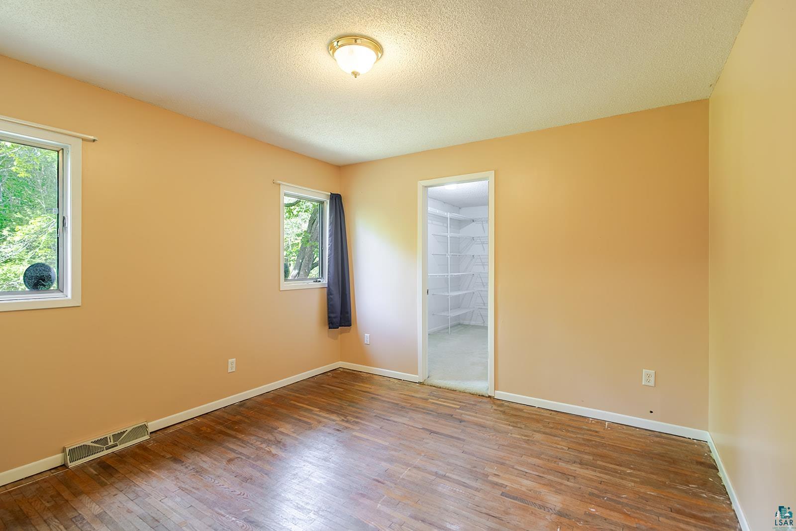 7045 Morris Thomas Road Cloquet, MN 55720 - Photo 11 of 28 Bedroom featuring wood-finish flooring, two windows with white trim, and a ceiling light fixture