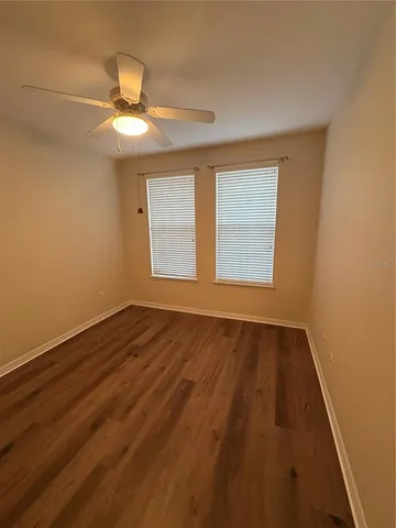 an empty room with wooden floor fan and windows