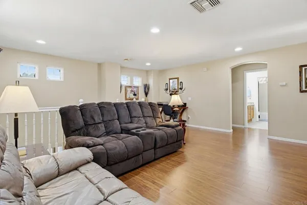 a living room with furniture a wooden floor and a lamp