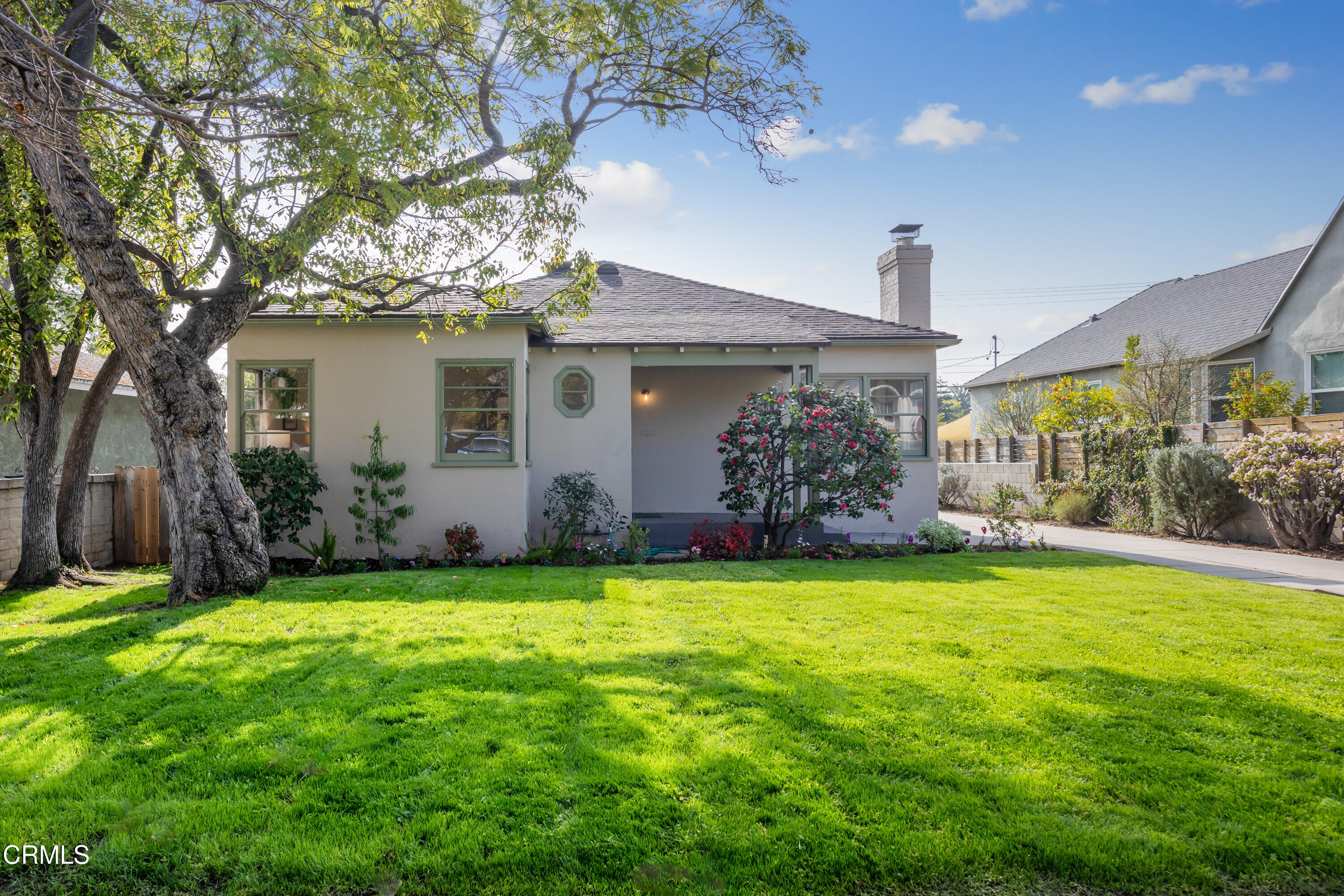 a view of a house with a yard and a large tree