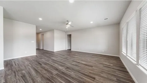 a view of an empty room with wooden floor and a window