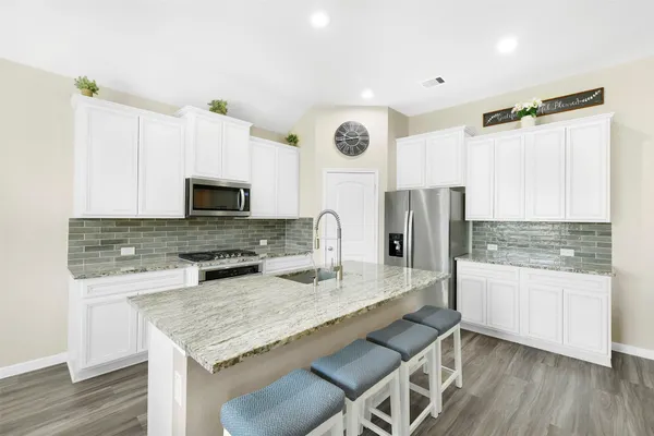 a kitchen with granite countertop a stove refrigerator and microwave