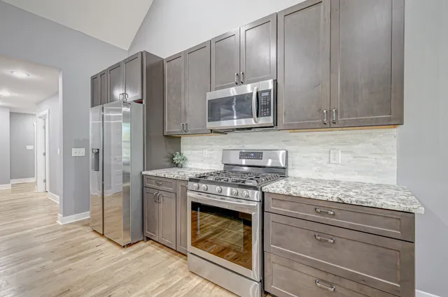 a kitchen with granite countertop wooden cabinets stainless steel appliances and a counter space