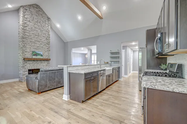 a kitchen with stainless steel appliances granite countertop a stove top oven a sink a refrigerator and white cabinets