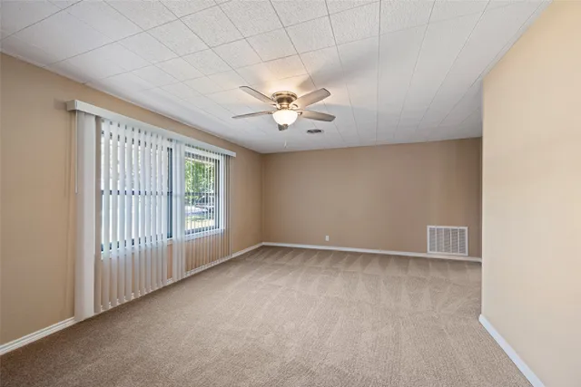 an empty room with windows and ceiling fan