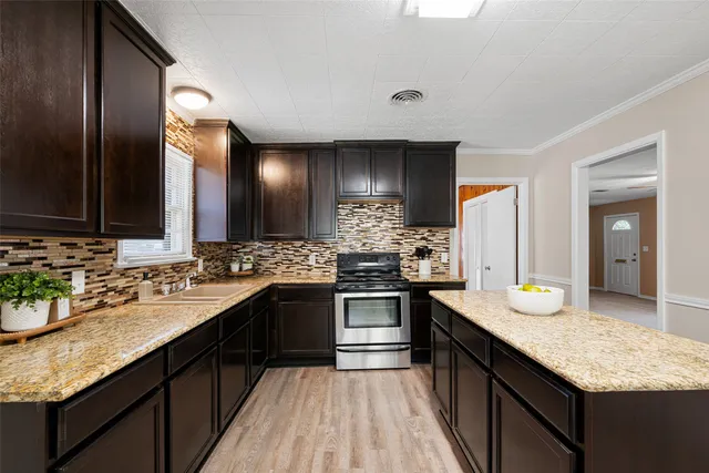 a large kitchen with granite countertop a sink dishwasher stove and refrigerator with wooden floor