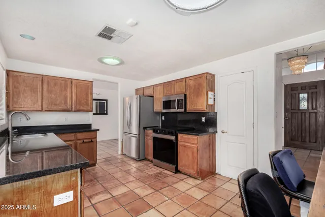 a kitchen with stainless steel appliances granite countertop a stove top oven a sink a dining table and chairs