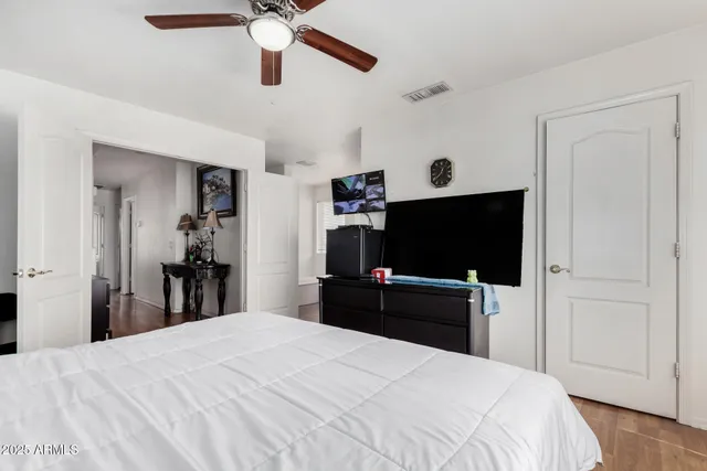a bedroom with a bed and a flat tv screen on dresser