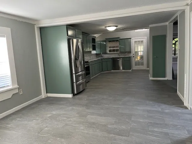 an empty room with a kitchen and a refrigerator