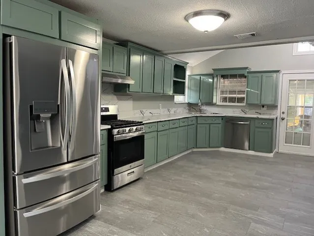 a kitchen with stainless steel appliances granite countertop a refrigerator and a sink
