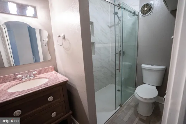 a bathroom with a granite countertop sink toilet and shower