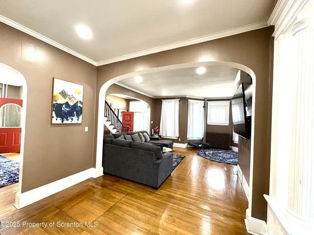 a living room with couches painting on the wall and a large window