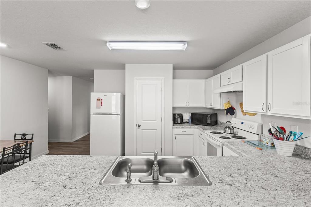 3332 Lambert Avenue Spring Hill, FL 34608 - Photo 11 of 30 a kitchen with stainless steel appliances granite countertop a sink a stove and a refrigerator