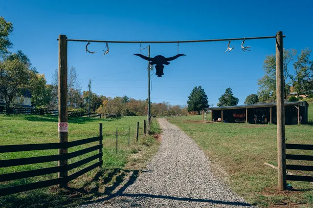 an aerial view of a residential houses with outdoor space and trees all around