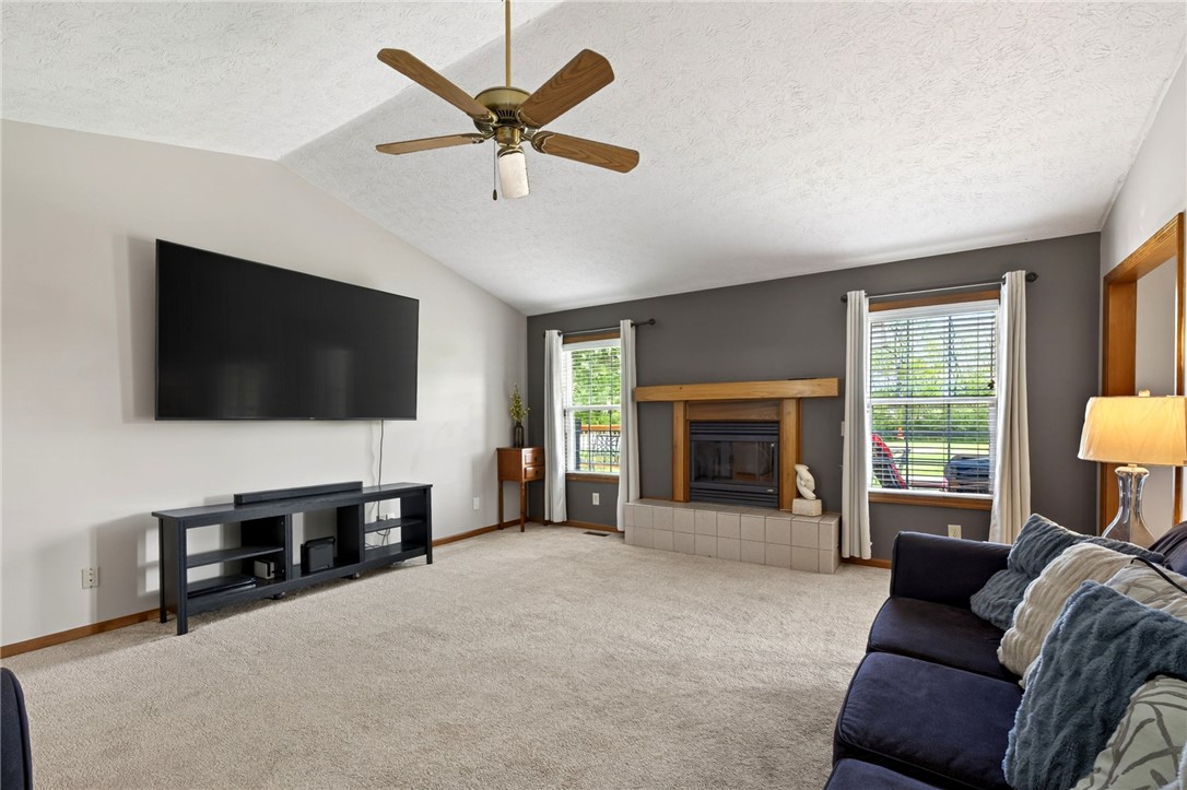 4996 Shannon Avenue Springfield, OH 45504 - Photo 20 of 61 This living room features a cozy fireplace, carpeted flooring, and a ceiling fan for comfort.