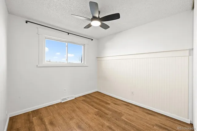 an empty room with a window and a ceiling fan