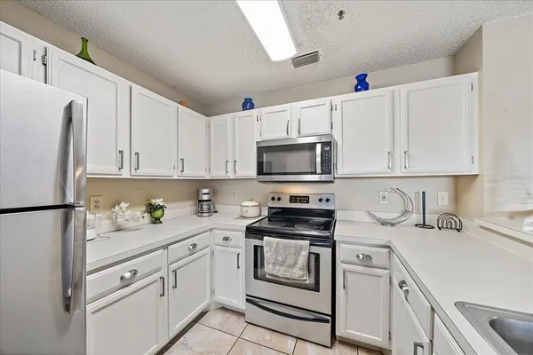 a kitchen with granite countertop white cabinets white stainless steel appliances and sink