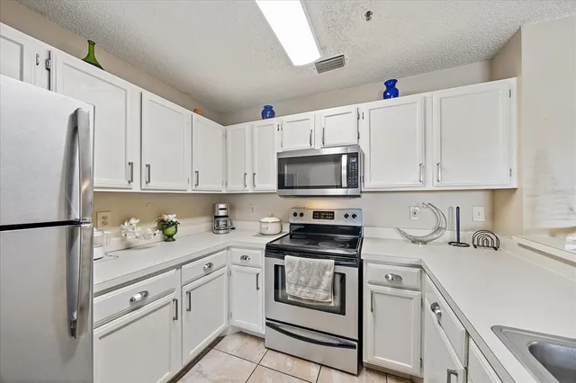 a kitchen with granite countertop white cabinets white stainless steel appliances and sink