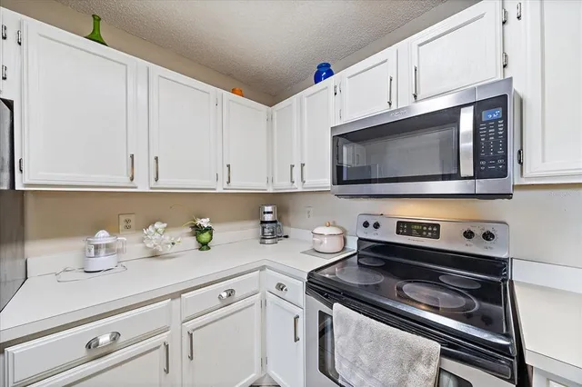 a kitchen with granite countertop white cabinets appliances and a sink