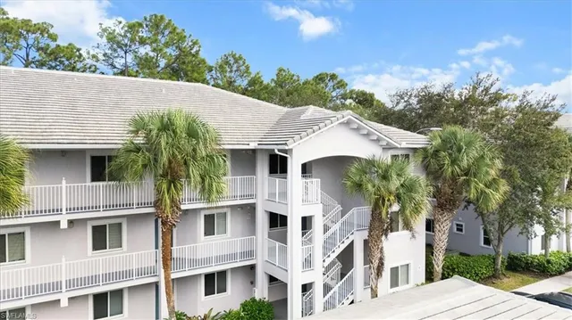 a view of a white house with a plants and a tree