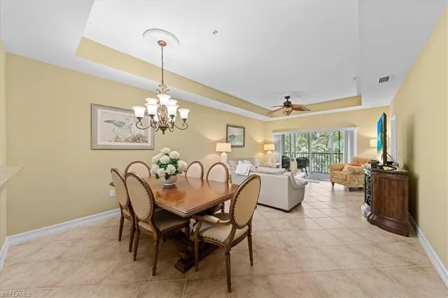 a dining room filled chandelier and kitchen view