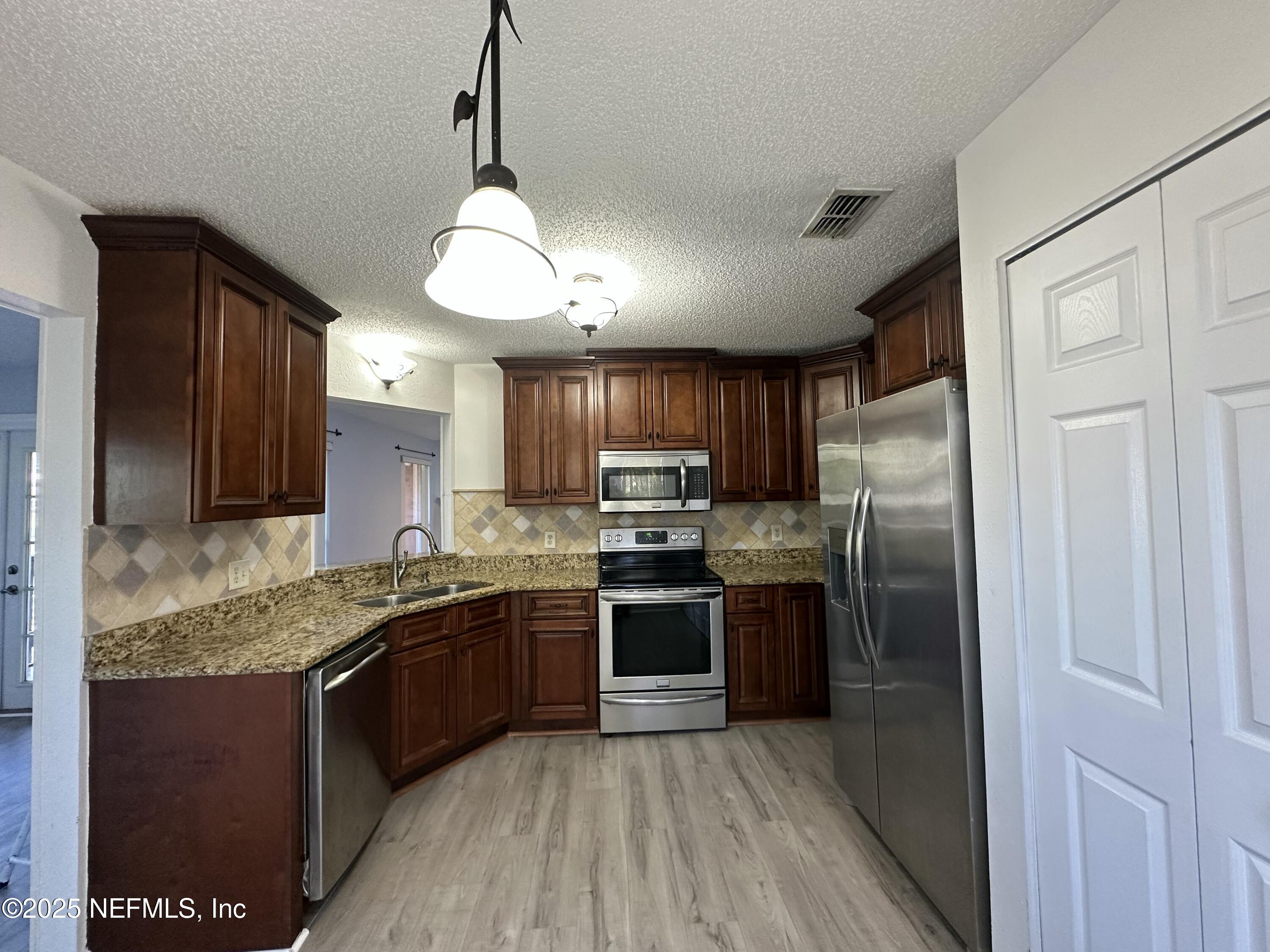 3801 Crown Point Road, Unit 3082 Jacksonville, FL 32257 - Photo 12 of 41 a kitchen with stainless steel appliances granite countertop refrigerator a stove top oven a sink and dishwasher