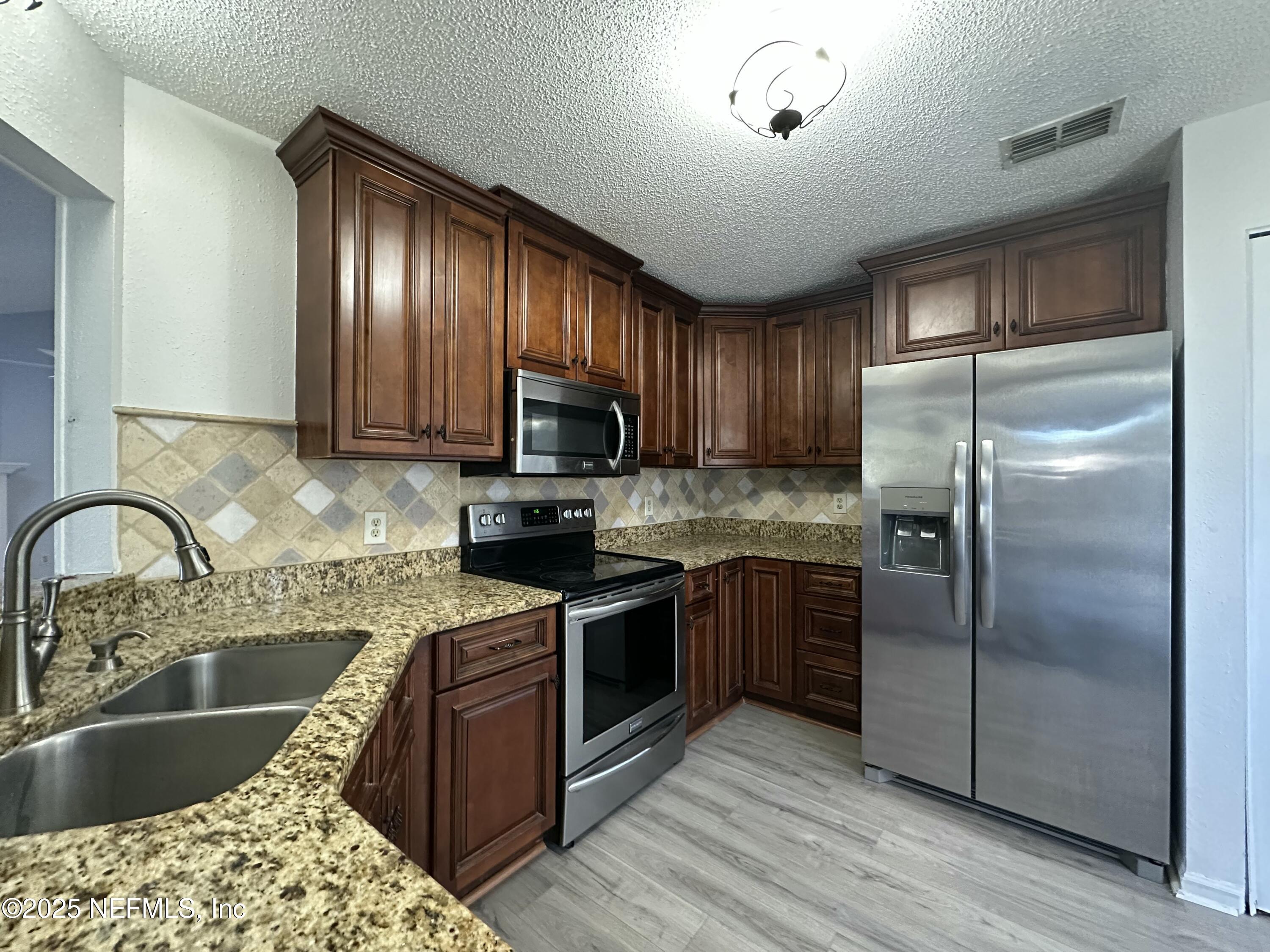 3801 Crown Point Road, Unit 3082 Jacksonville, FL 32257 - Photo 13 of 41 a kitchen with granite countertop a sink stainless steel appliances and wooden cabinets